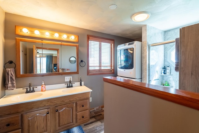 bathroom featuring washer / clothes dryer, double vanity, an enclosed shower, and wood finished floors