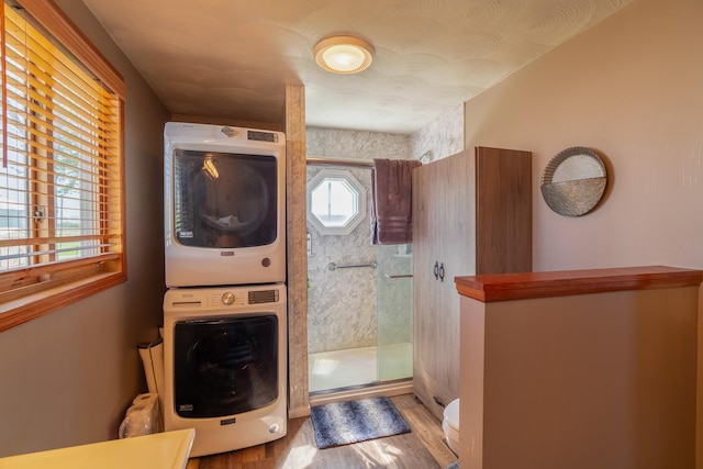 washroom with stacked washer and clothes dryer and wood finished floors
