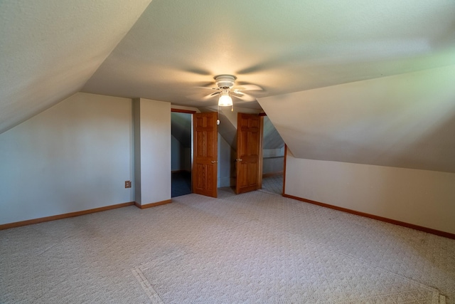 bonus room with vaulted ceiling, light colored carpet, ceiling fan, and baseboards