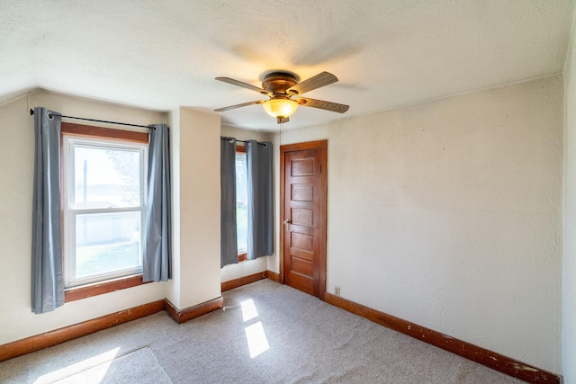 carpeted empty room with ceiling fan, baseboards, and vaulted ceiling