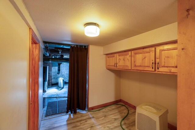 mudroom featuring light wood-style flooring, baseboards, and a textured ceiling