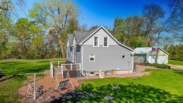 rear view of house featuring a lawn, a deck, and an outbuilding