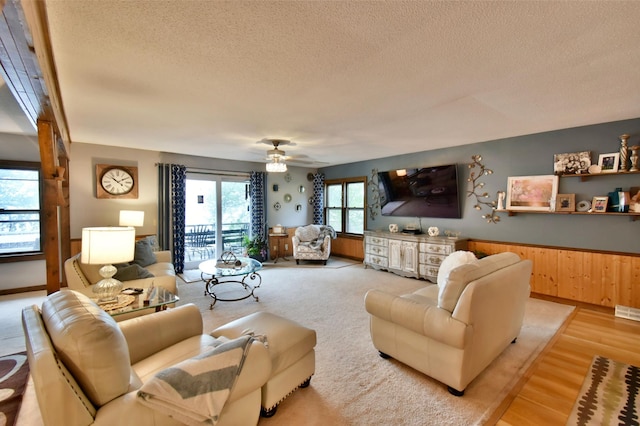 5151 99th Ave, Clear Lake, MN 55319 - living area featuring a textured ceiling, wainscoting, light wood-style flooring, a ceiling fan, and wood walls