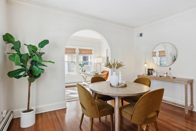dining area with a baseboard radiator, wood finished floors, ornamental molding, baseboards, and arched walkways