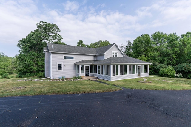 15126 Tumuli Rd, Dalton, MN 56324 - view of front of property with a sunroom, a shingled roof, and a front lawn