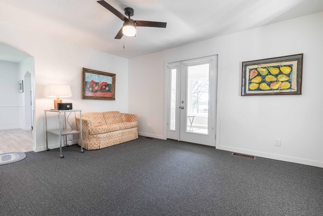 15126 Tumuli Rd, Dalton, MN 56324 - living room featuring arched walkways, dark carpet, ceiling fan, and baseboards