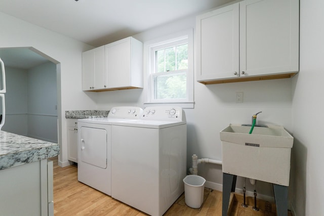 15126 Tumuli Rd, Dalton, MN 56324 - clothes washing area featuring cabinet space, separate washer and dryer, light wood finished floors, and arched walkways