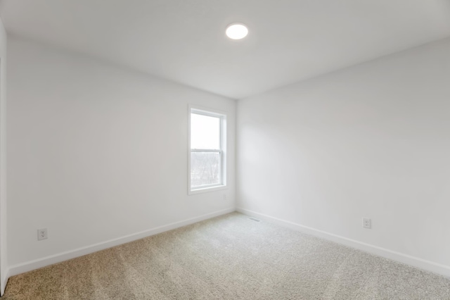 carpeted empty room featuring baseboards