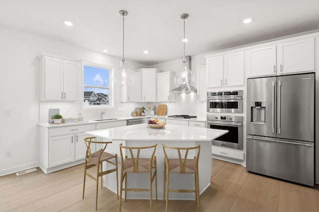 kitchen featuring appliances with stainless steel finishes, a sink, light wood-type flooring, light countertops, and recessed lighting