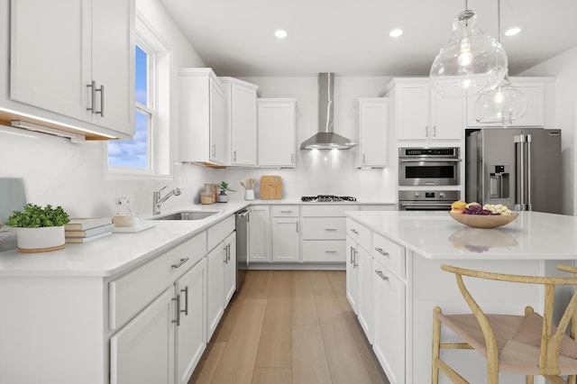 kitchen featuring wall chimney range hood, appliances with stainless steel finishes, a breakfast bar area, white cabinets, and recessed lighting