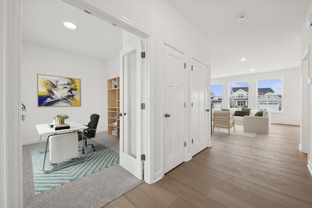 hallway with wood finished floors, an office area, baseboards, and recessed lighting
