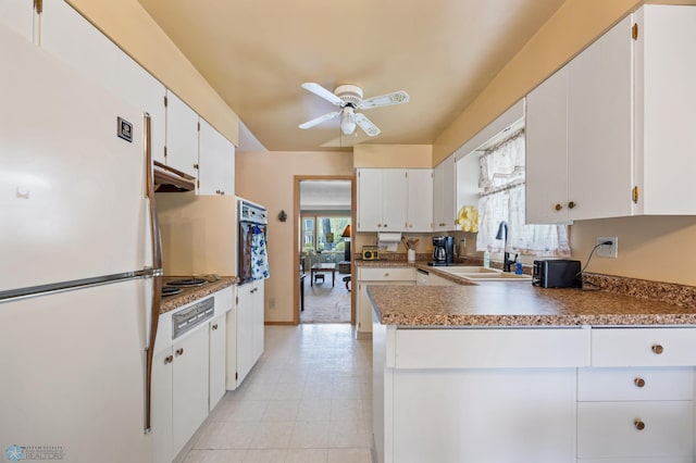 kitchen featuring freestanding refrigerator, a sink, a ceiling fan, stainless steel oven, and white cabinetry