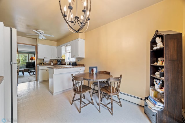 dining area with a baseboard heating unit, ceiling fan, a chandelier, and light flooring