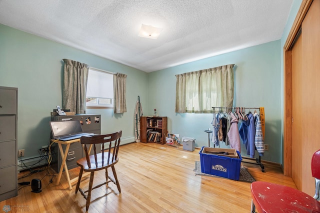 office space with wood finished floors, a textured ceiling, and a baseboard radiator