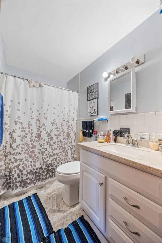 bathroom with toilet, vanity, tile walls, a shower with shower curtain, and marble look tiles
