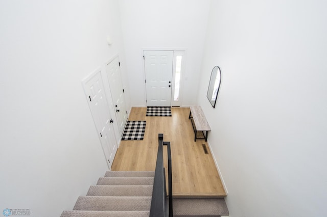 staircase featuring a high ceiling, wood finished floors, and baseboards
