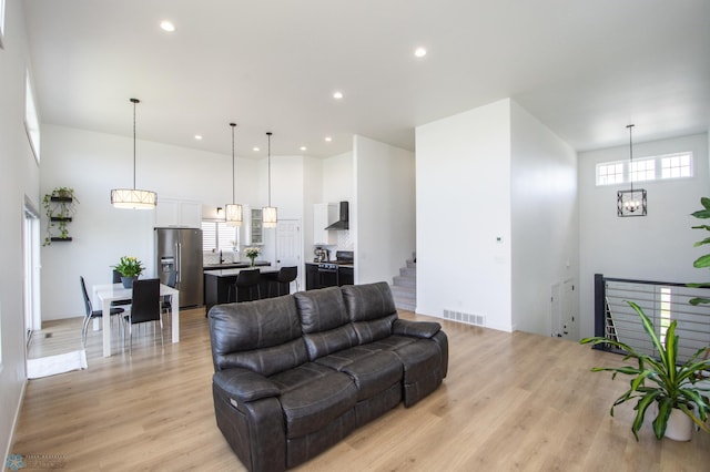 living area featuring light wood finished floors, recessed lighting, and a high ceiling