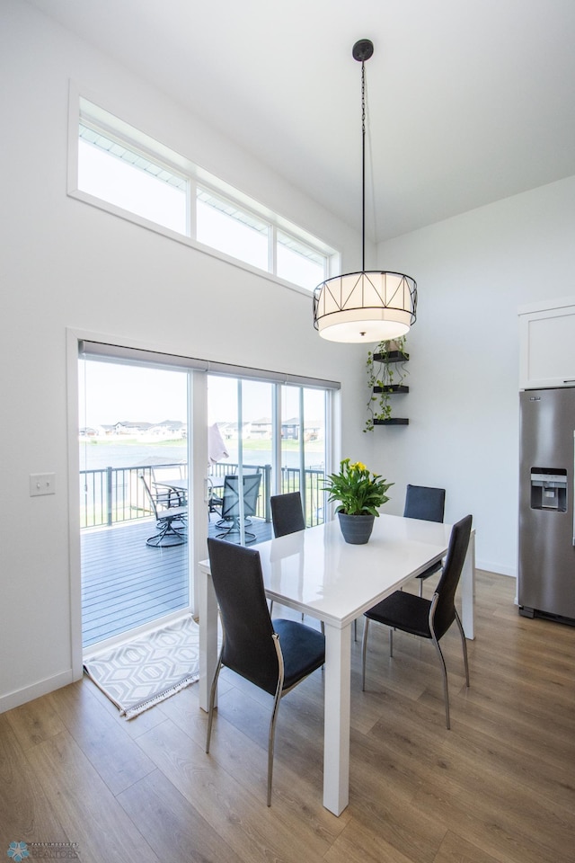 dining area featuring wood finished floors, baseboards, and a towering ceiling