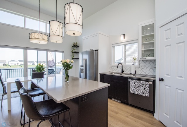 kitchen featuring stainless steel appliances, a sink, high vaulted ceiling, a kitchen breakfast bar, and backsplash