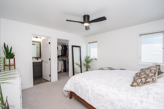 bedroom with light colored carpet, a walk in closet, connected bathroom, a closet, and a ceiling fan