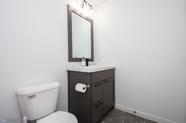half bathroom featuring baseboards, vanity, toilet, and marble finish floors