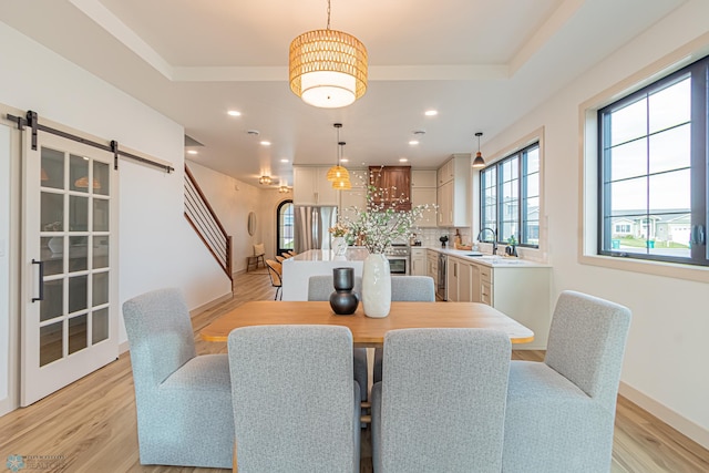 8820 Northern Lights Ave, Fargo, ND 58047 - dining room featuring light wood-type flooring, a barn door, recessed lighting, baseboards, and a raised ceiling
