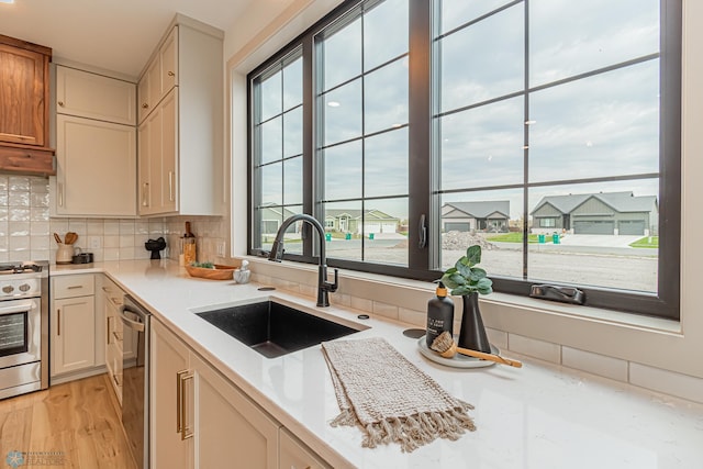 8820 Northern Lights Ave, Fargo, ND 58047 - kitchen featuring a sink, stainless steel appliances, backsplash, light wood finished floors, and under cabinet range hood