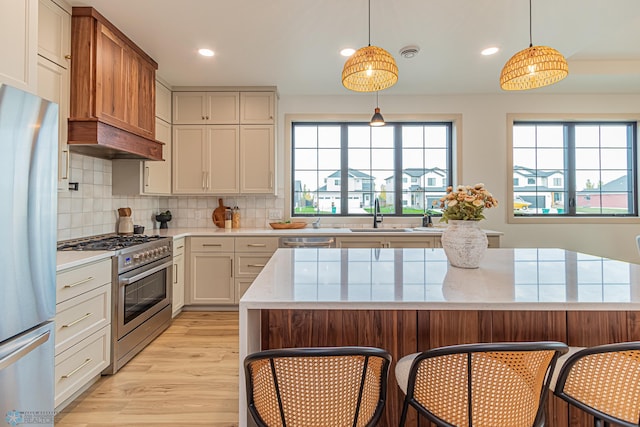 8820 Northern Lights Ave, Fargo, ND 58047 - kitchen with stainless steel appliances, a sink, light wood-style flooring, backsplash, and a kitchen breakfast bar