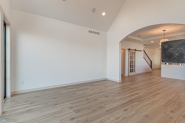 8820 Northern Lights Ave, Fargo, ND 58047 - unfurnished room with arched walkways, a barn door, light wood finished floors, recessed lighting, and high vaulted ceiling