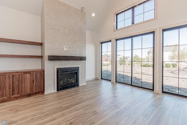 8820 Northern Lights Ave, Fargo, ND 58047 - unfurnished living room featuring high vaulted ceiling, light wood-type flooring, a fireplace, baseboards, and recessed lighting