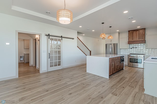 8820 Northern Lights Ave, Fargo, ND 58047 - kitchen with stainless steel appliances, light countertops, a barn door, backsplash, and light wood-style floors