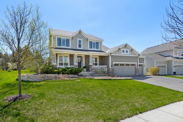 view of front facade featuring covered porch, asphalt driveway, a front yard, and stone siding