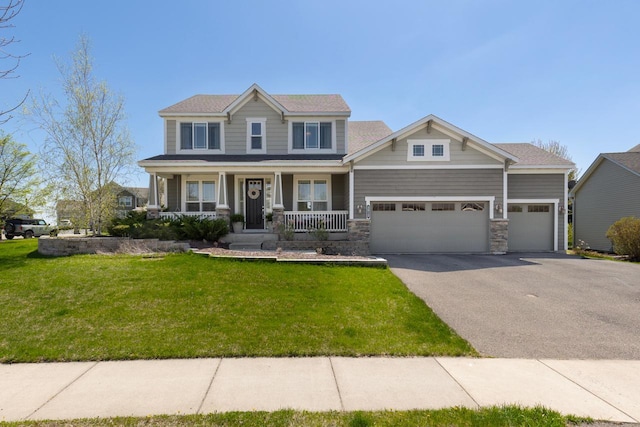 craftsman inspired home with asphalt driveway, a porch, a front yard, a garage, and stone siding