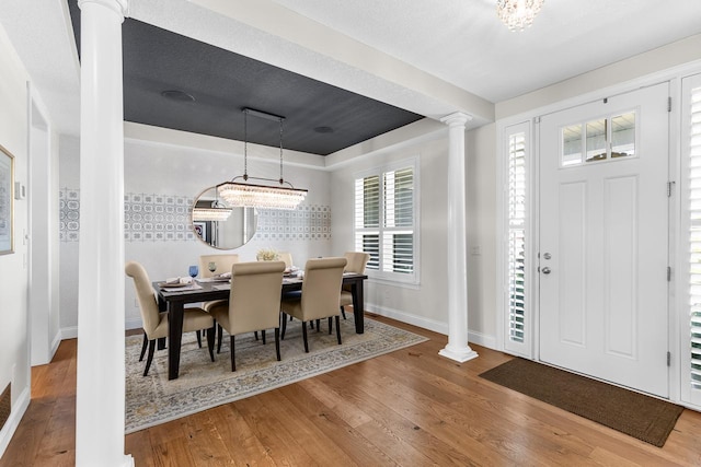 dining area with ornate columns, baseboards, and wood finished floors