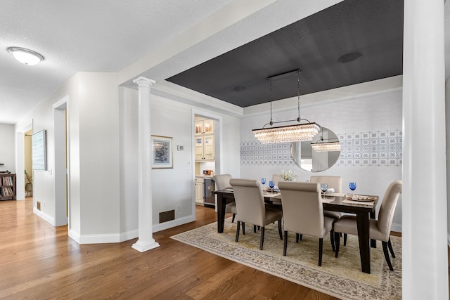 dining area with wood finished floors, decorative columns, and baseboards