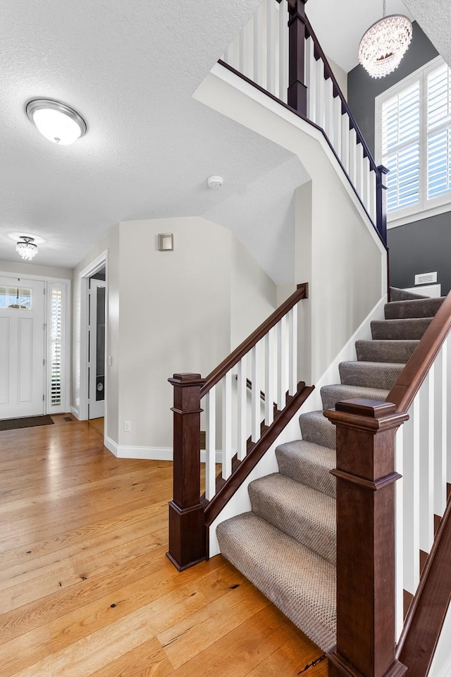 stairs featuring hardwood / wood-style flooring, plenty of natural light, baseboards, and a textured ceiling