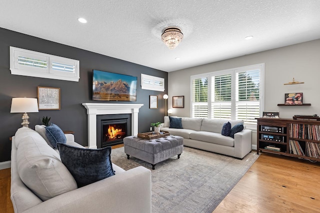 living area featuring light wood finished floors, a textured ceiling, recessed lighting, and a lit fireplace