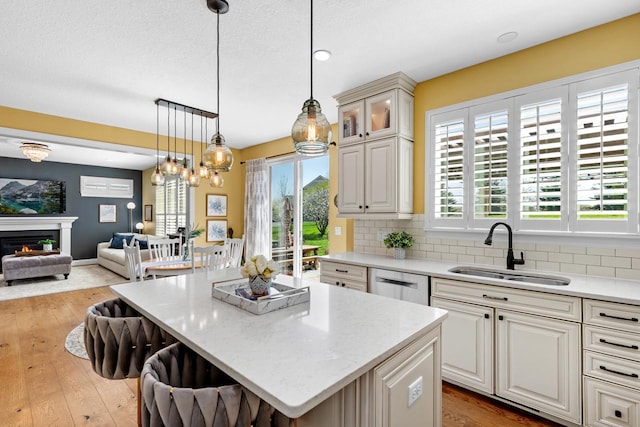kitchen featuring a sink, dishwasher, open floor plan, a kitchen island, and light wood-style floors
