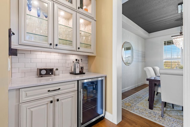 indoor dry bar with wine cooler, baseboards, dark wood-type flooring, and backsplash