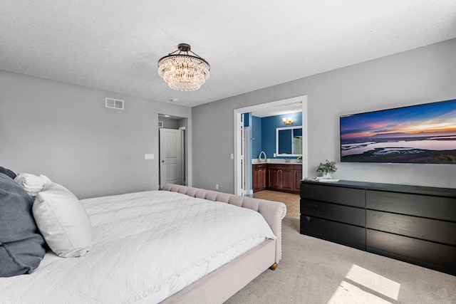 bedroom with light colored carpet, a chandelier, and ensuite bath