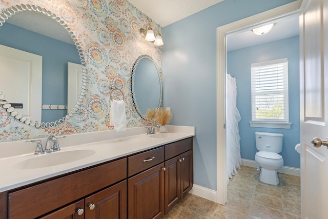 bathroom featuring double vanity, toilet, tile patterned floors, and baseboards