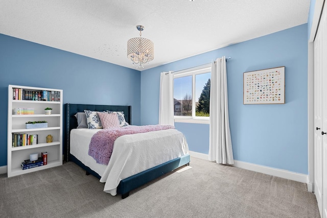 carpeted bedroom with baseboards and a chandelier
