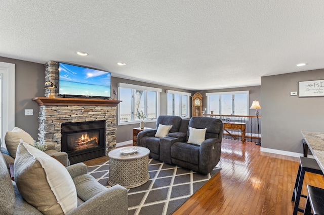 1683 Hansack Ave NE, Saint Michael, MN 55376 - living area featuring wood-type flooring, a textured ceiling, a stone fireplace, baseboards, and recessed lighting