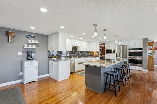 1683 Hansack Ave NE, Saint Michael, MN 55376 - kitchen with stainless steel appliances, a sink, light wood-style floors, white cabinetry, and a textured ceiling