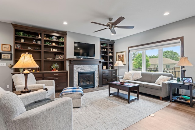 2006 13th Ave NE, Austin, MN 55912 - living room with wood finished floors, a stone fireplace, a ceiling fan, recessed lighting, and built in shelves