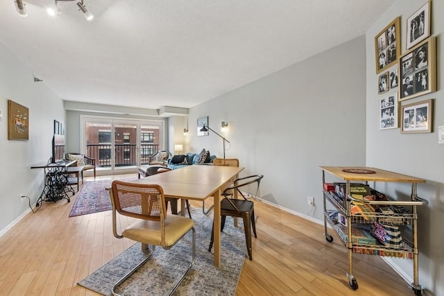dining area featuring light wood-style flooring and baseboards