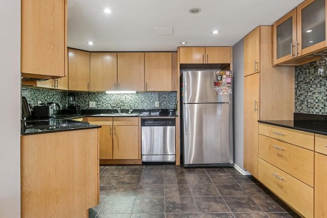 kitchen featuring stainless steel appliances, dark countertops, a sink, tasteful backsplash, and recessed lighting