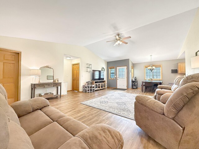 living room with wood finished floors, vaulted ceiling, ceiling fan, a chandelier, and baseboards