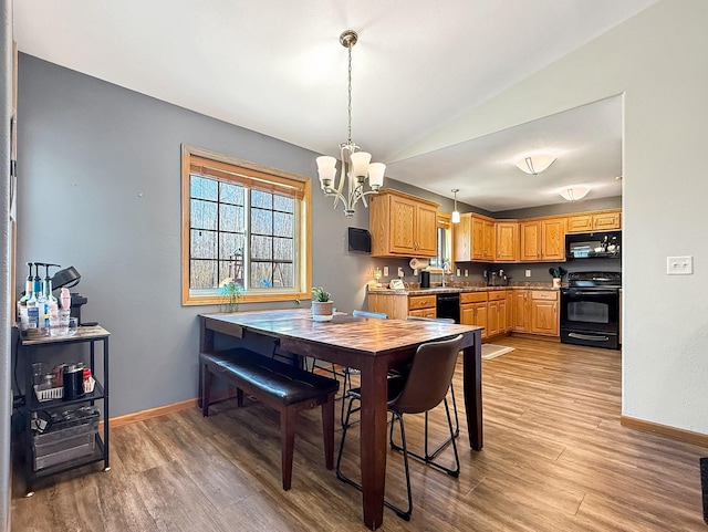 dining area with a chandelier, baseboards, light wood-type flooring, and vaulted ceiling