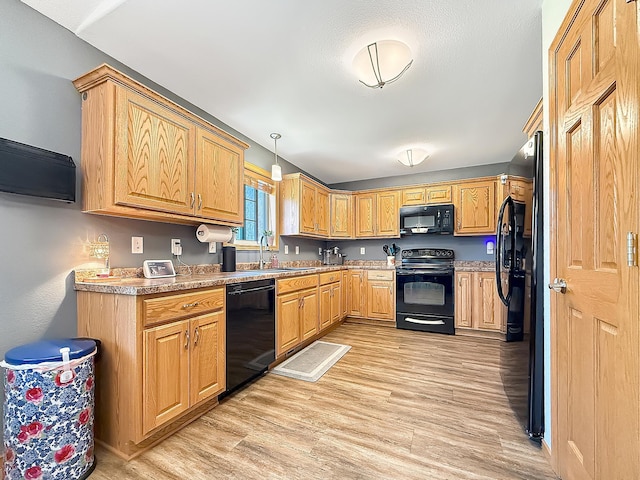 kitchen featuring black appliances, light wood-style floors, a sink, and light countertops